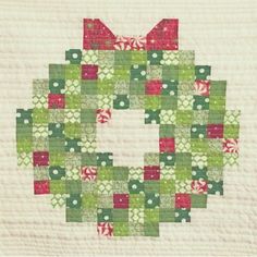 a green, red and white quilted square with a bow on it's center