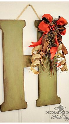 a wooden letter hanging on the side of a door with a wreath attached to it