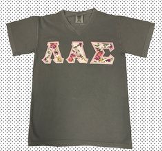 a gray shirt with pink letters and flowers on it