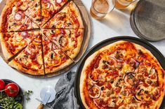 two pizzas sitting on top of pans next to each other with toppings