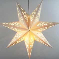 a white paper star hanging from the ceiling with light shining through it's center