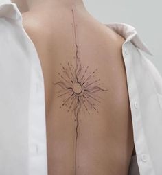 the back of a woman's shoulder with a sun tattoo