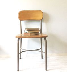 a stack of books sitting on top of a wooden chair next to a white wall