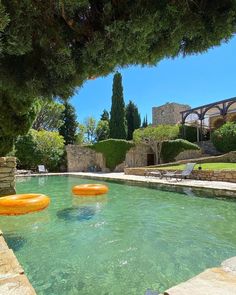 an outdoor swimming pool with inflatable floats floating on it's sides and trees