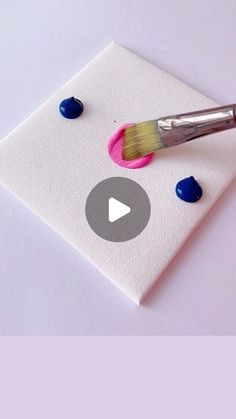 a paintbrush sitting on top of a piece of paper with blue and white dots