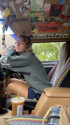 a woman sitting in the back seat of a car with lots of items on it