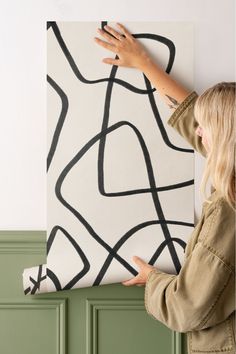 Person applying abstract line wallpaper with bold black strokes on a neutral background, ideal for a modern, minimalist interior style. Abstract Line Wallpaper, Line Wallpaper, Doodle Wall, Cool Doodles, Earthy Colours, Lines Wallpaper, Black And Beige, Neutral Decor, Wallpaper Mural