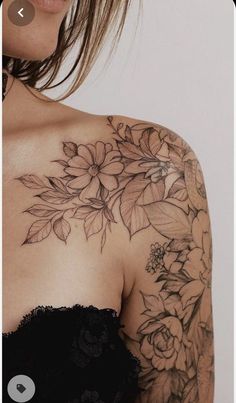 the back of a woman's shoulder with flowers and leaves tattooed on her arm