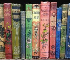 a row of colorful books sitting on top of a book shelf next to each other