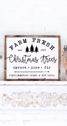 a christmas tree sign on top of a mantle in front of a white brick wall