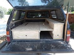 an open trunk in the back of a pickup truck with wooden drawers on the bed