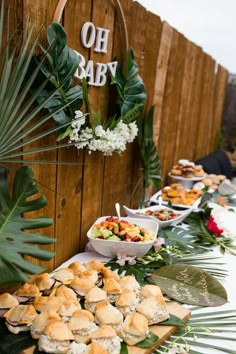 a buffet table filled with lots of food on it's sides and palm leaves