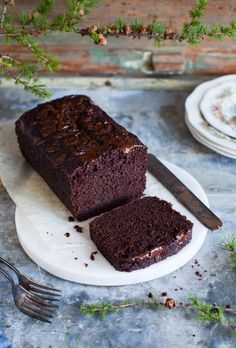 a piece of chocolate cake on a plate with a knife and fork next to it