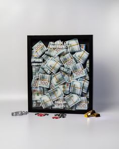 a pile of money sitting inside of a black frame next to two stacks of coins