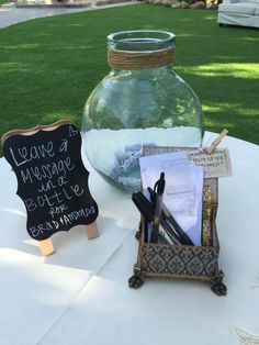 there is a glass jar with writing on it next to a chalkboard and pen holder