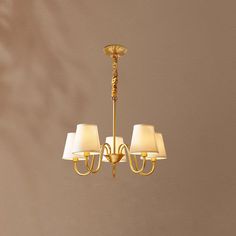 a gold chandelier with four lamps hanging from it's sides and two shades on each side