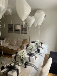 balloons and gifts are on the table for a party with white flowers in vases