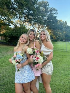 three beautiful young women standing next to each other holding bouquets in their hands and posing for the camera