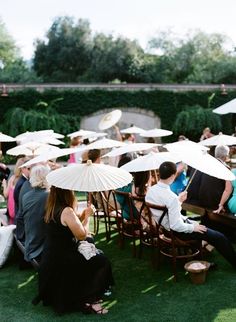 people sitting on lawn chairs with umbrellas over their heads and in the back ground