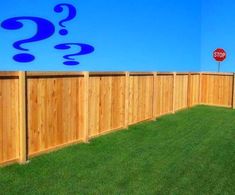 a wooden fence in front of a blue wall with question marks on it and a stop sign