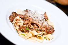 a white plate topped with pasta and meat