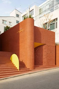 a brick building with steps leading up to it and a yellow door on the side