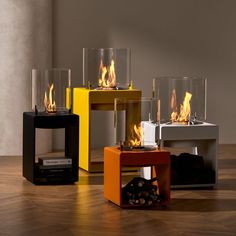 three different colored tables with fire burning in them on top of wooden flooring area