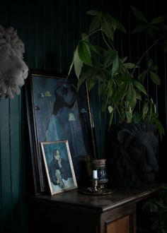 there is a painting on the table next to a potted plant and framed pictures