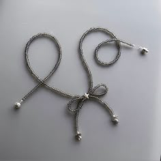 a silver necklace with pearls and beads on a white surface, in the shape of an octopus