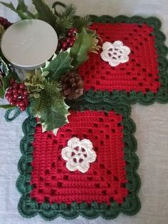 two crocheted placemats sitting on top of a table next to a candle