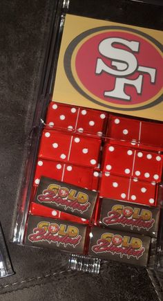 six red dices with white polka dots are sitting in a clear case on the floor