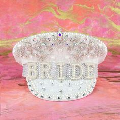 a white bridal clutch with pearls and jewels on it, sitting on a pink background