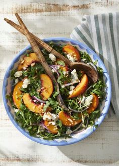 a salad with peaches and feta cheese in a blue bowl on a table