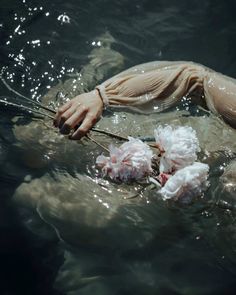 a person floating in the water with flowers on their head and hands above his body