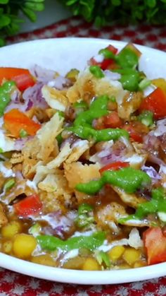 a white bowl filled with vegetables on top of a red and white checkered table cloth