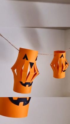 some orange paper cups are hanging from a line with string lights on them and jack - o'- lantern faces