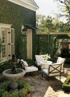 an outdoor living room with white furniture and greenery on the walls is featured in this instagram