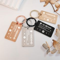 four different types of keychains and tags on a white surface with flowers in the background