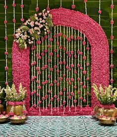 a pink and white wedding backdrop with flowers on the front, along with gold vases