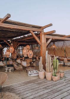 an outdoor seating area with chairs, tables and cacti on the deck at sunset