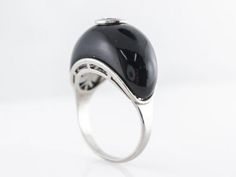 This Mid-Century onyx cocktail ring features a .72 carat round brilliant cut diamond set in platinum atop a piece of smooth black onyx. The black onyx and diamond look has been around for a long time, probably because it looks so great! This ring has such a unique design because of the smooth curved shape of the onyx. A rare find and one that you will love! Composition: Platinum Ring Size: 7.50 -- ALL PIECES ARE SUBJECT TO PRIOR SALE DUE TO HAVING A RETAIL LOCATION. -- 10-DAY RETURN POLICY FREE Modern Black Enamel Rings For Formal Events, Modern Black Enamel Rings For Formal Occasions, Elegant Black Dome Ring With Polished Finish, Elegant Evening Rings With Center Stone, Formal Black Dome Ring With Polished Finish, Elegant Evening Diamond Ring With Gemstone, Modernist Diamond Ring For Formal Occasions, Modern White Gold Diamond Ring For Evening, Luxury Dome Ring With Center Stone For Formal Events