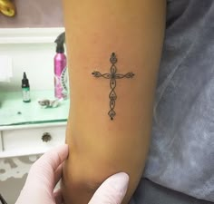 a person holding their arm with a cross tattoo on it's left side,