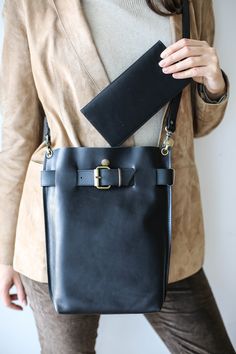 a woman is holding a black leather bag