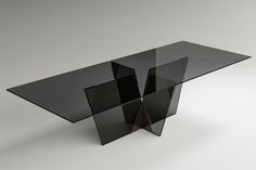 a black glass table sitting on top of a white floor next to a gray wall