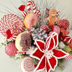 a christmas arrangement with candy canes, candies and other holiday decorations on a white surface