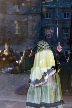 the reflection of a woman in a dress holding an umbrella is seen through a window