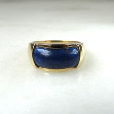 This is a 14K yellow gold ring set with a blue lapis lazuli stone.  The inside of the band is stamped 14K & PacG.  The ring is sized at a 7.  Total weight of the ring is 6.1 grams.  The ring face is 9mm long x 15mm wide.   This is a vintage, previously owned ring.  Therefore, light wear can be expected.  There is no visible damage.