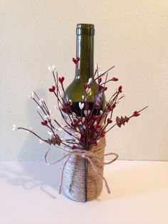 a wine bottle wrapped in twine and tied to a vase with flowers inside it