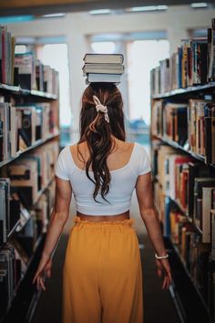 a woman standing in front of a book shelf with books on top of her head