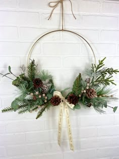 a wreath with pine cones and greenery hanging on a brick wall